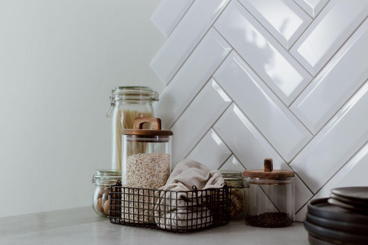 contact-img Stylish kitchen setup featuring glass jars with pasta and grains on a clean counter.