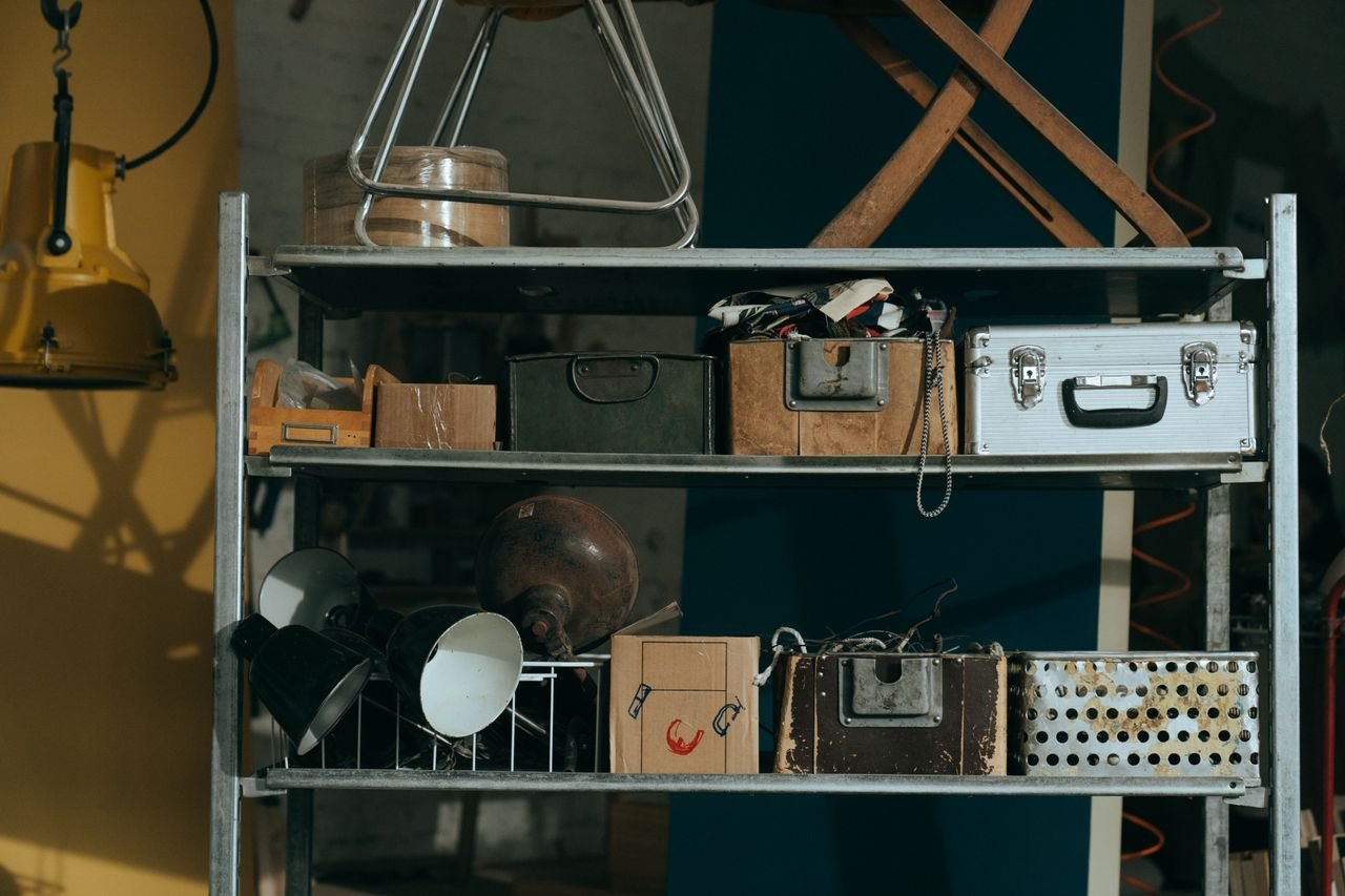 services-01 A shelf in a workshop holding vintage and retro objects, showcasing old storage boxes and tools.